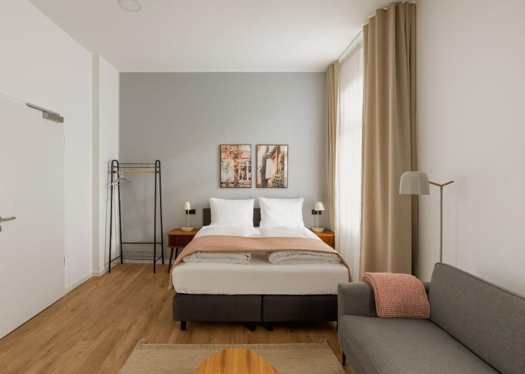a bedroom with a bed and a couch at Limehome Kaiserslautern Rummelstr in Kaiserslautern