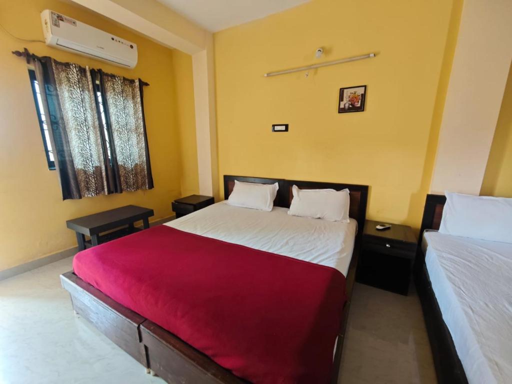 a bedroom with two beds and a red blanket at Carvalhos Regina 100 mtrs Patnem beach in Canacona