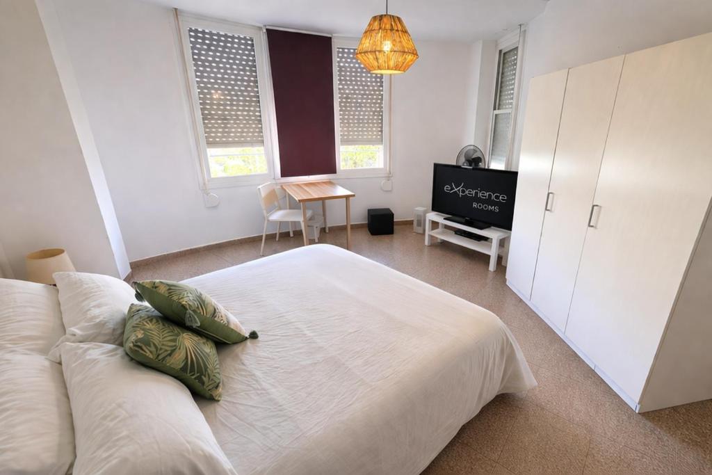 a bedroom with a white bed with pillows on it at eXperience Rooms Valencia in Valencia