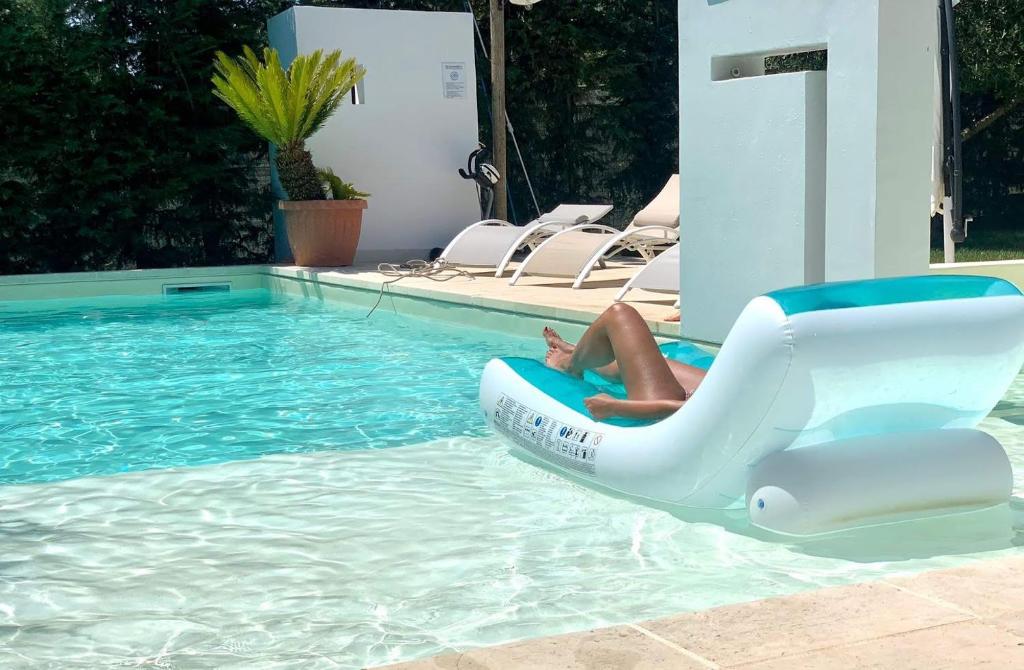 a person laying on a raft in a swimming pool at Dimora San Quirico - b&b Cisternino Valle D'Itria in Cisternino