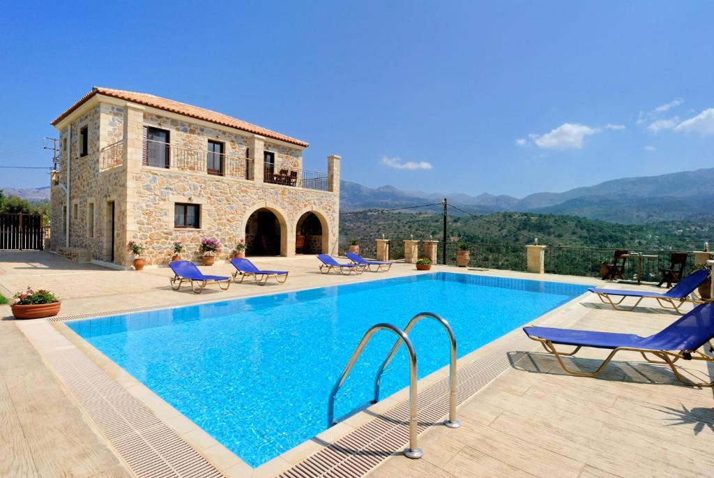 a swimming pool with blue chairs and a house at Villa Georgia in Fílippos