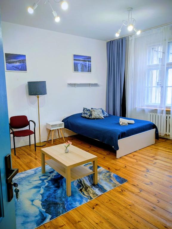 a bedroom with a blue bed and a table at Pokoje Rybnicka 10 in Katowice