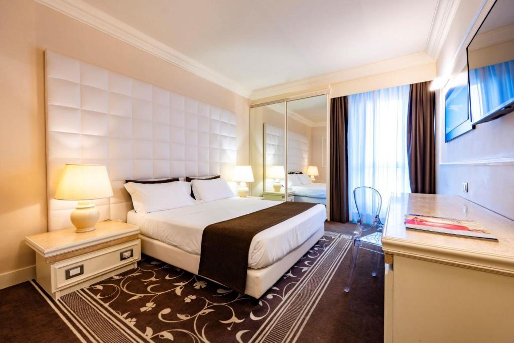a hotel room with a bed and a table and a mirror at Etrusco Arezzo Hotel - Sure Hotel Collection by Best Western in Arezzo