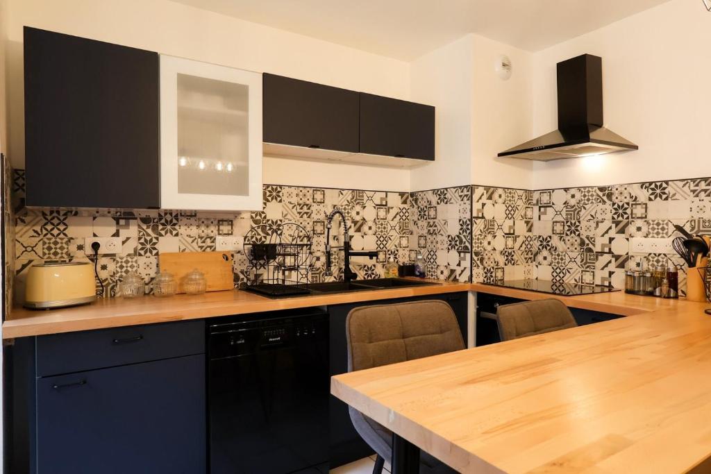 a kitchen with black and white wallpaper and a wooden counter at Le Saint Regis - Hyper centre. in Le Puy-en-Velay