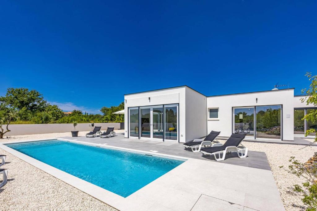 a villa with a swimming pool and lounge chairs at Villa Karolina by Villa Plus in Štokovci