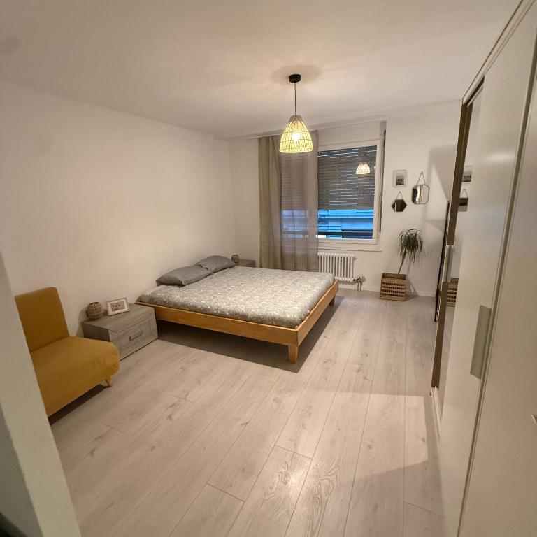 a bedroom with a bed and a chair and a window at Appt Lausanne Gare - Totti in Lausanne