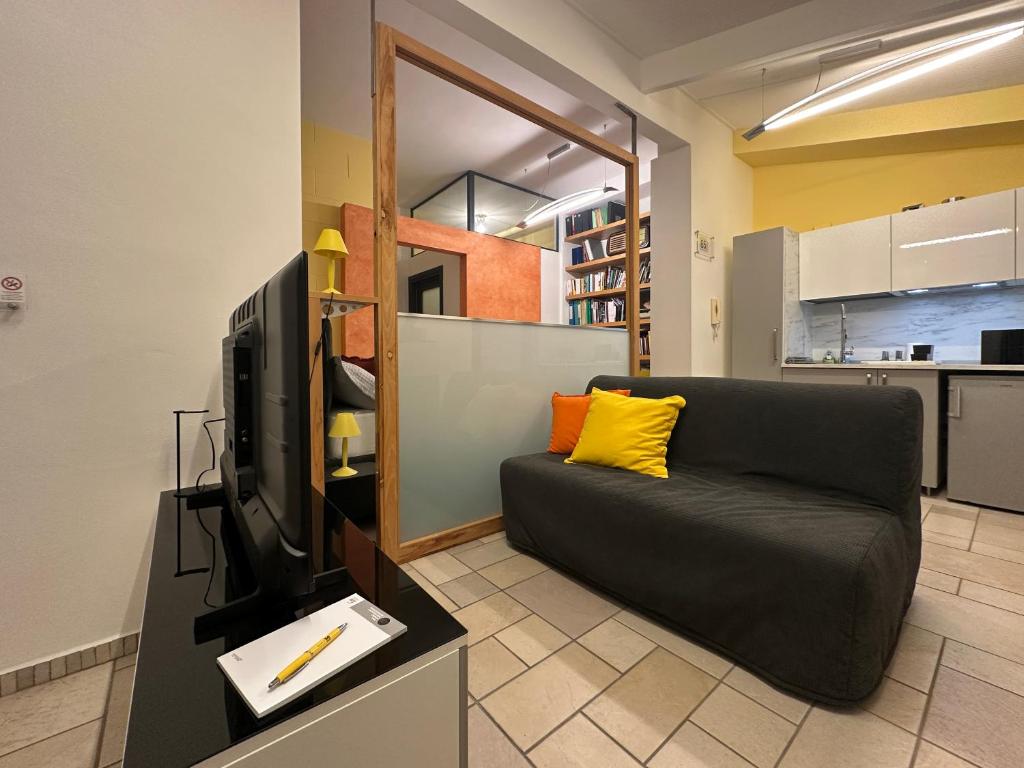 ein Wohnzimmer mit schwarzem Sofa und Fernseher in der Unterkunft Casa 65 in Pontedera