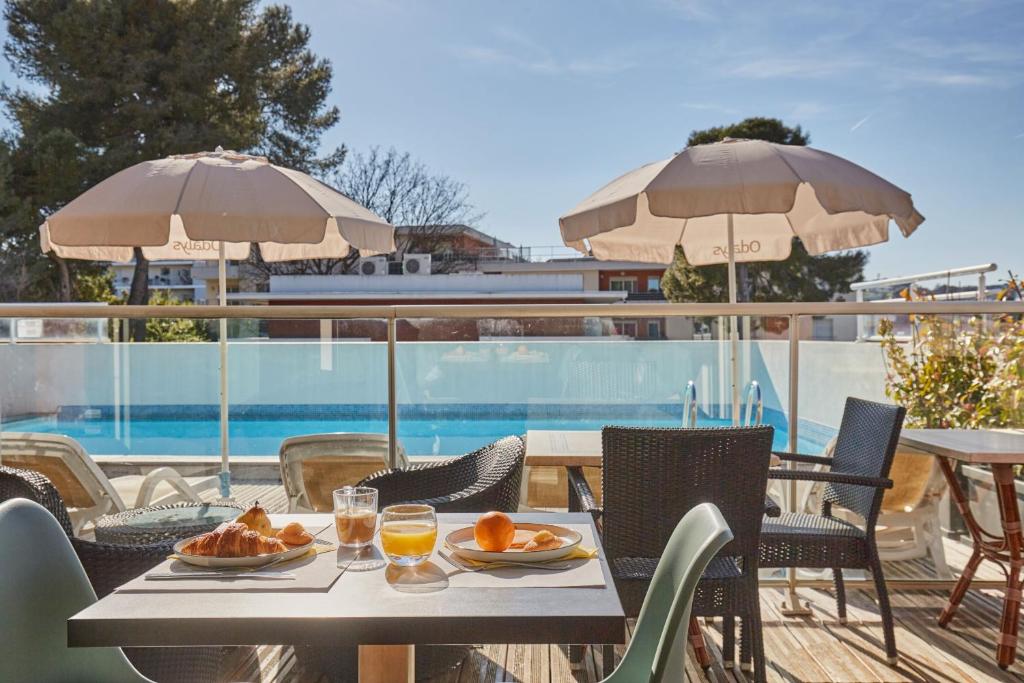 a table with plates of food and drinks on a patio at Appart'hôtel Odalys City - Antibes Olympe in Antibes