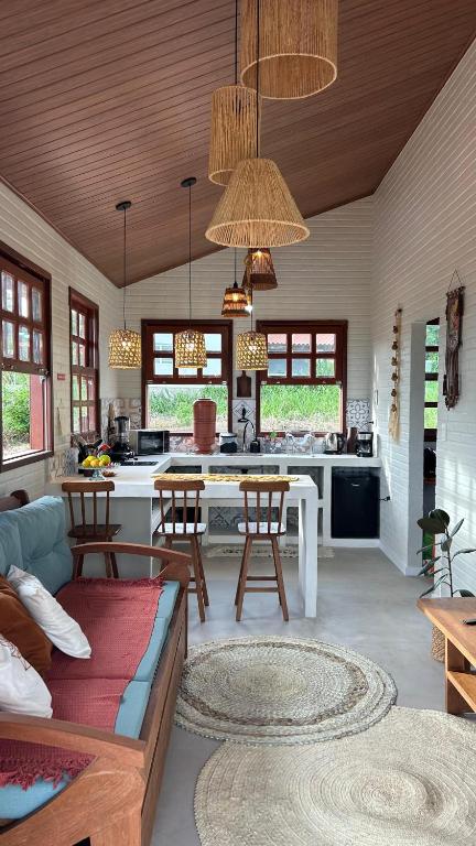 a kitchen and living room with a table and chairs at Vila do Sussurro - Casinha Céu in Triunfo