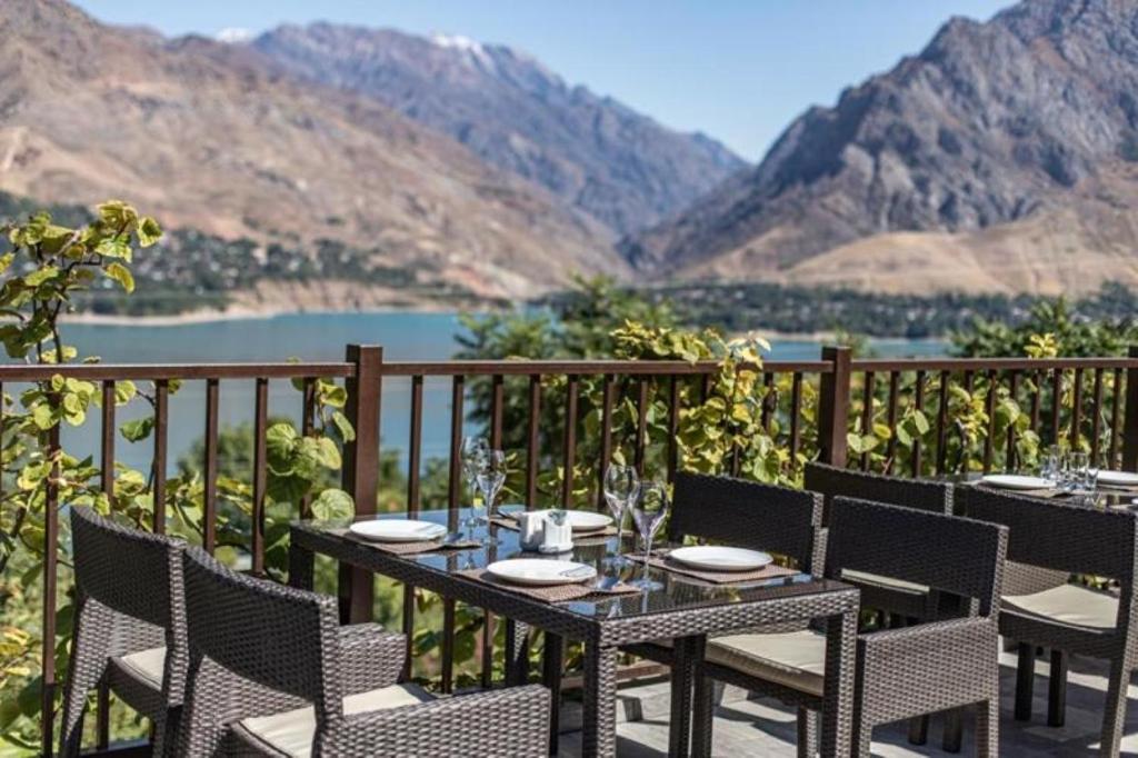 a table and chairs on a balcony with a view of a lake at Avenue Park Hotel in Yusufkhona