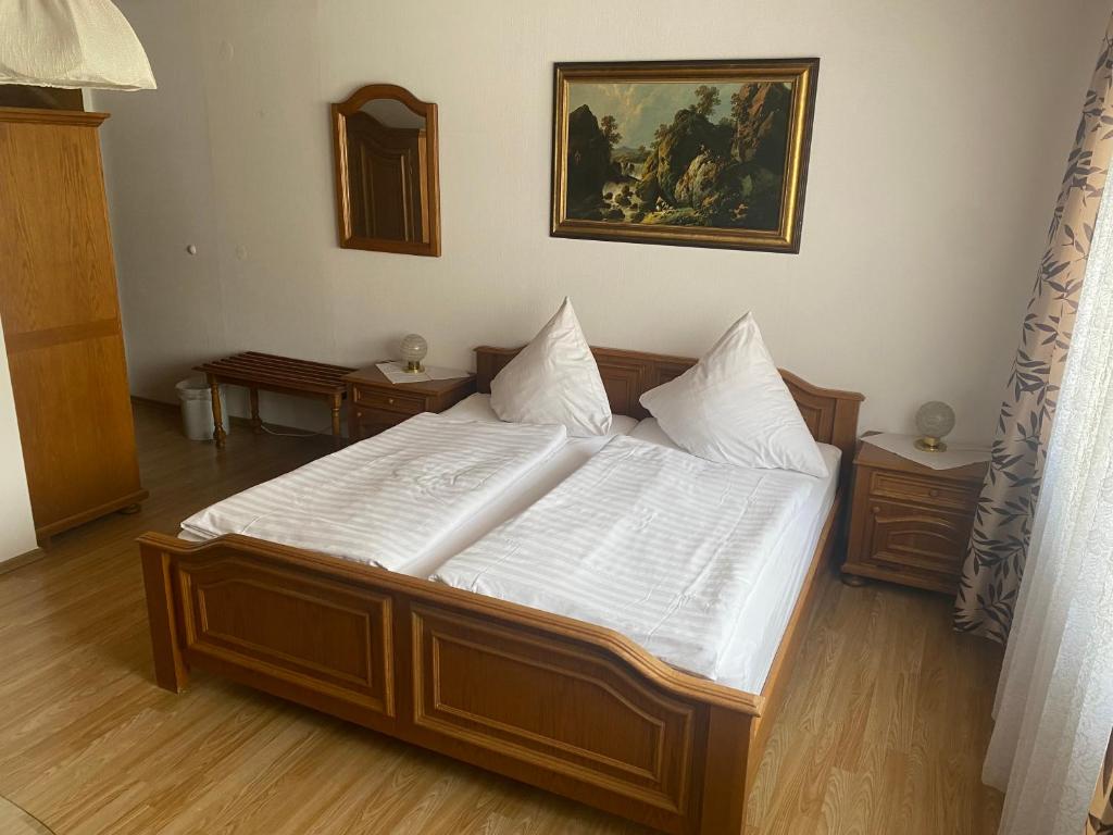 a bedroom with a large bed with white sheets at Gästehaus Wildfein in Wilnsdorf