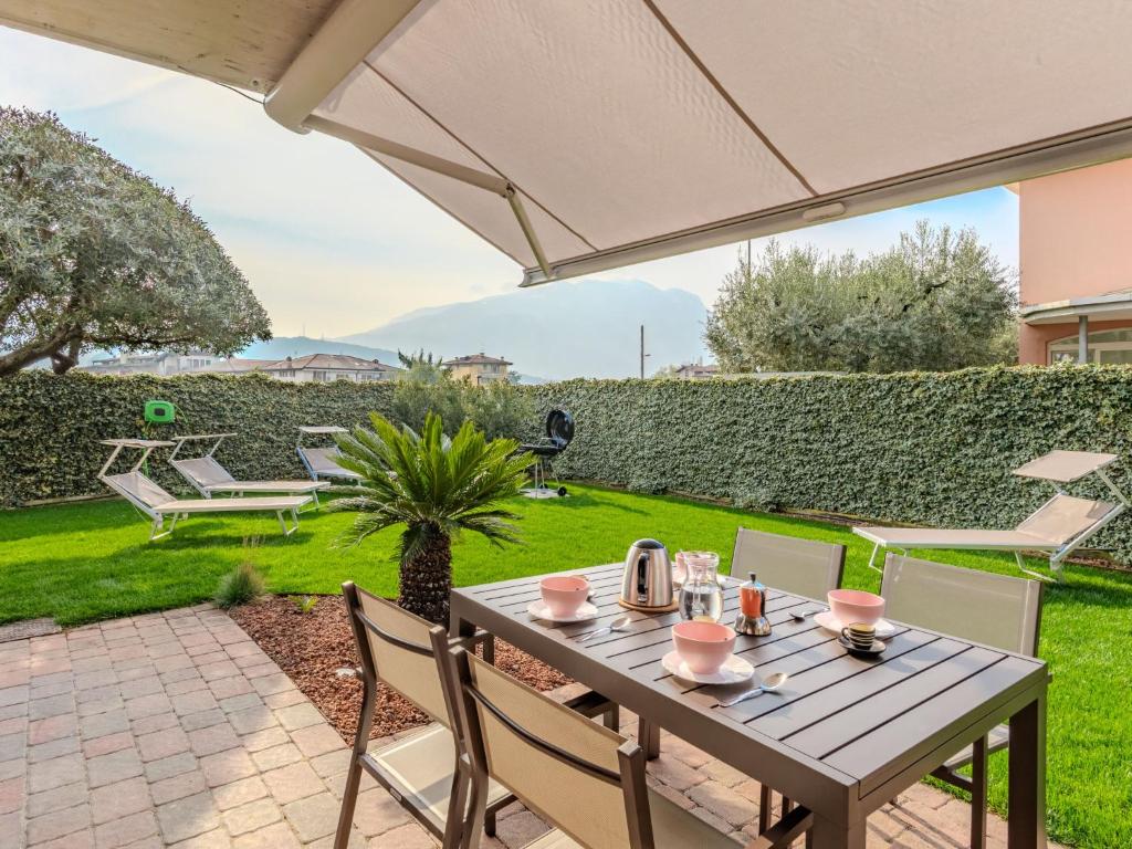 a table with chairs and an umbrella on a patio at Apartment Garda Oasis by Interhome in Riva del Garda