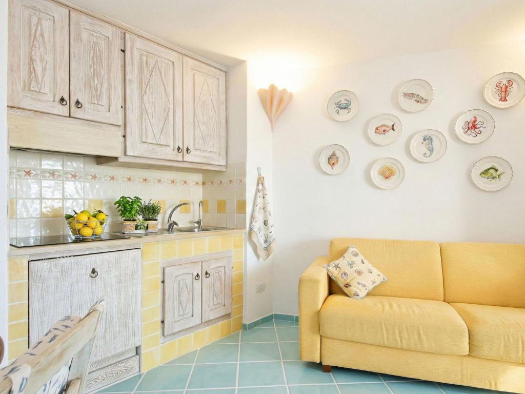 a living room with a yellow couch in a kitchen at Apartment Vista 9 by Interhome in Porto Cervo