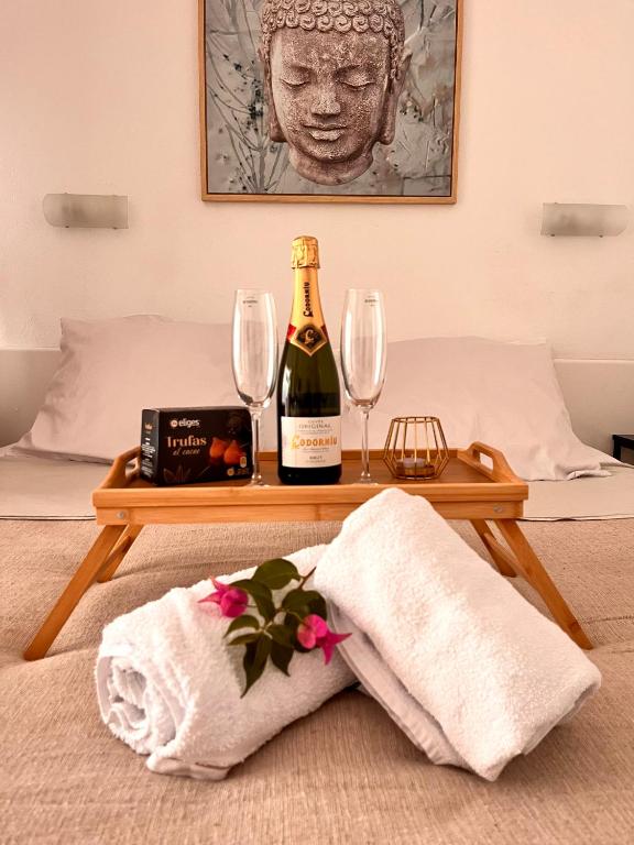 a table with a bottle of wine and glasses on a bed at Hotel Apartamentos Fuengirola private studio in Fuengirola