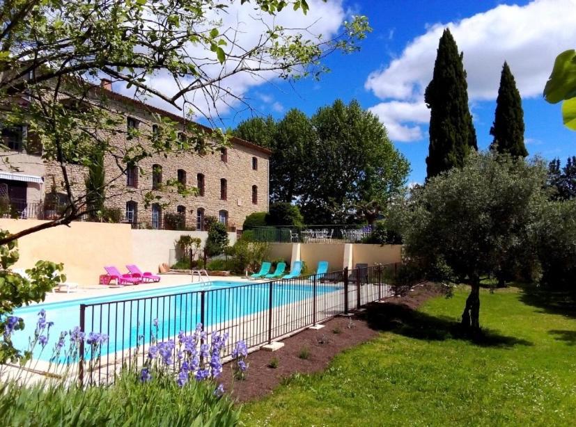 a swimming pool in a yard next to a building at Charmant studio à Viens in Viens