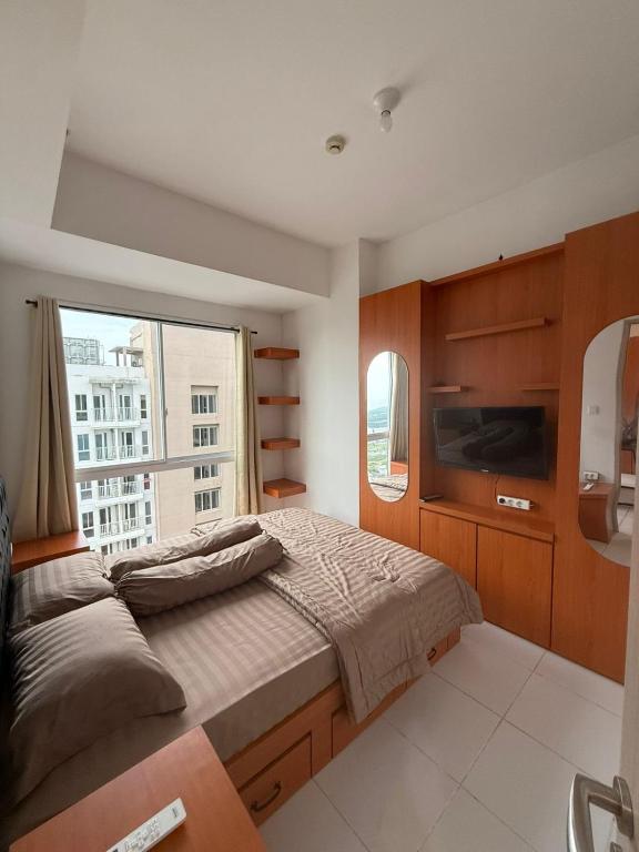 a bedroom with a bed and a large window at Modern 2BR Apartment With Fast WiFi in Rawalumpang