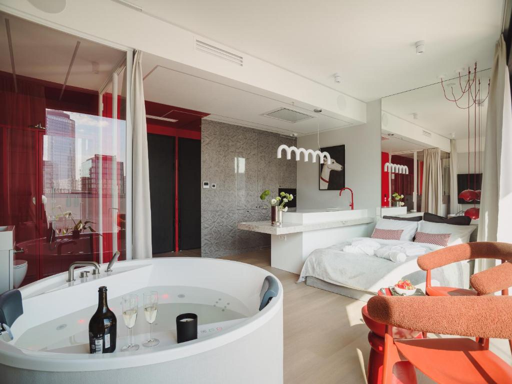 a bathroom with a bath tub and a bedroom at Scarlet Jacuzzi Suit by Sofija in Warsaw
