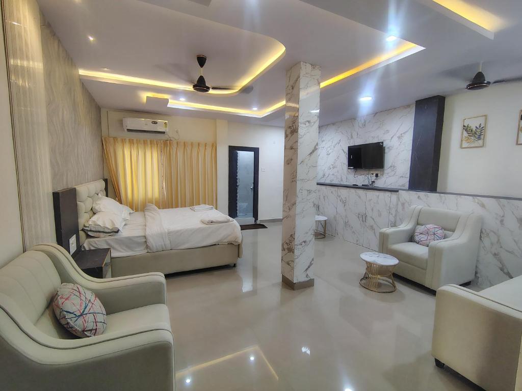 a bedroom with a bed and two chairs and a tv at HoTEL MOKSHA GRAND in Vijayawāda