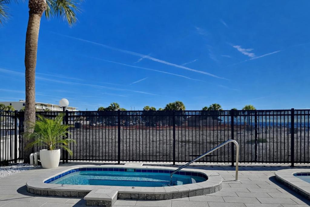 a swimming pool in front of a fence with a palm tree at Arie Dam 404 in St. Pete Beach