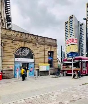 a train station with a man standing in front of it at Victoria Rooms in Manchester