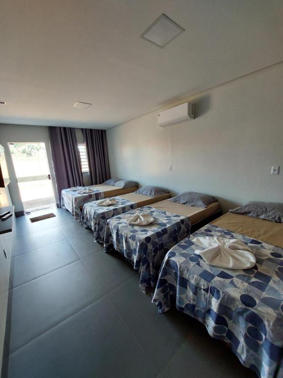 a row of beds in a room with a kitchen at Suíte Big Família - Queens Hotel in Formosa