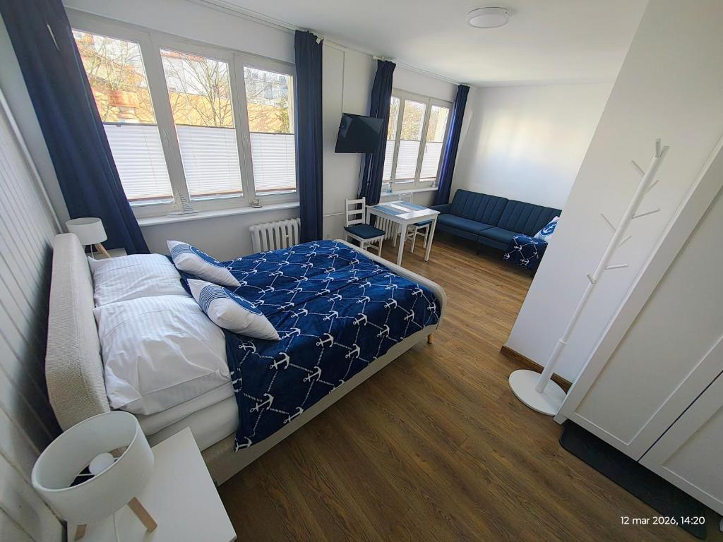 a bedroom with a bed with a blue comforter at Gryfhaus - Pokój Kapitański, 19m2, blisko plaży, parking, wysoka ocena 9,5, 2-4 osoby in Międzyzdroje