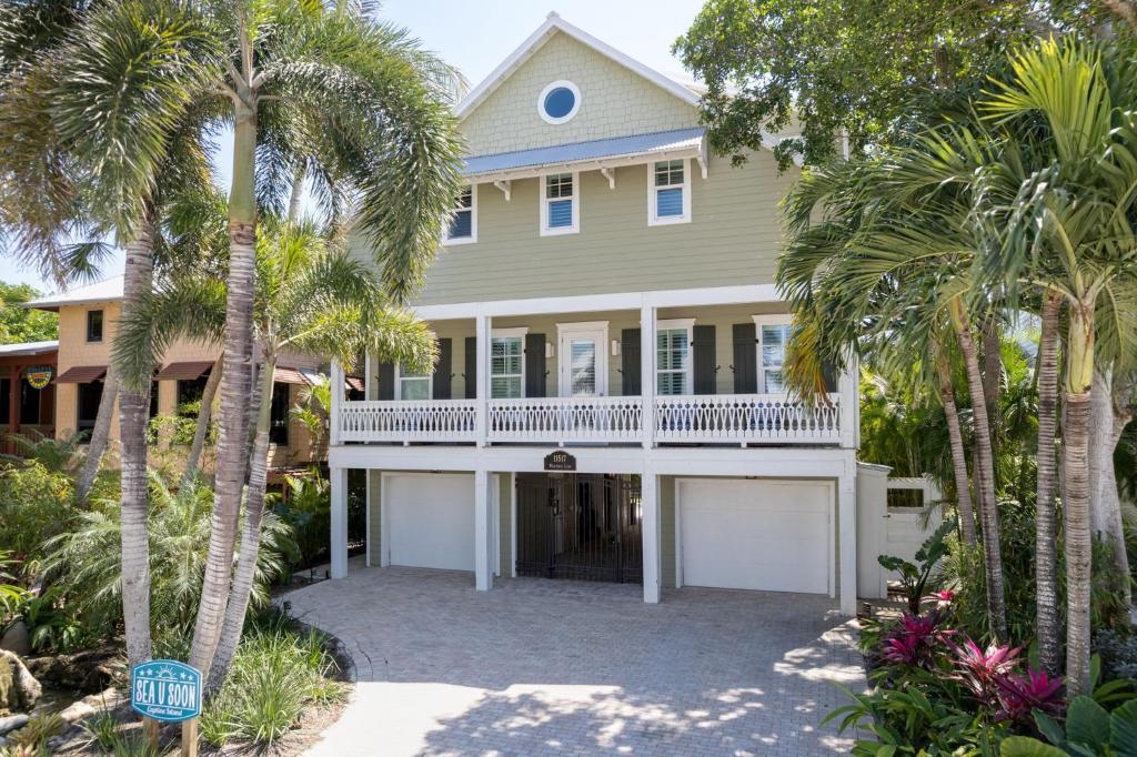 a house with palm trees in front of it at Sea U Soon - Premier 4 Bedroom Villa with Heated Pool in Captiva
