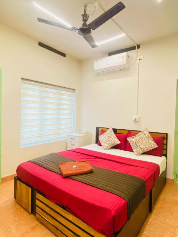 a bedroom with a large bed with a ceiling fan at Calathea home varkala beach in Varkala