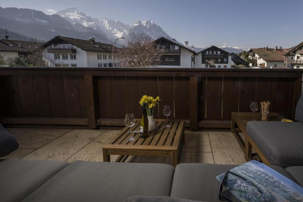 a balcony with a table and wine glasses and mountains at Ferienwohnung MehrBlick in Garmisch-Partenkirchen