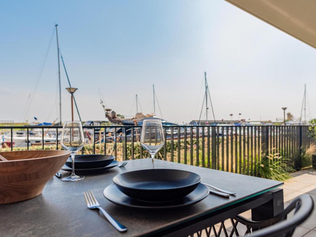 a table with plates and wine glasses on a balcony at Het Havenverblijf in Kamperland