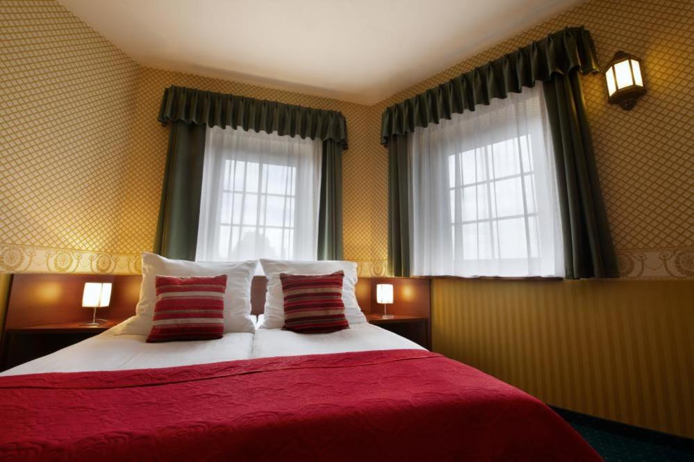 1 dormitorio con 1 cama con sábanas rojas y 2 ventanas en Noclegi I Restauracja Zodiak, en Gliwice