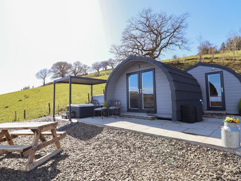 a tiny house with a patio and a picnic table at Cennin Pedr in Ruthin