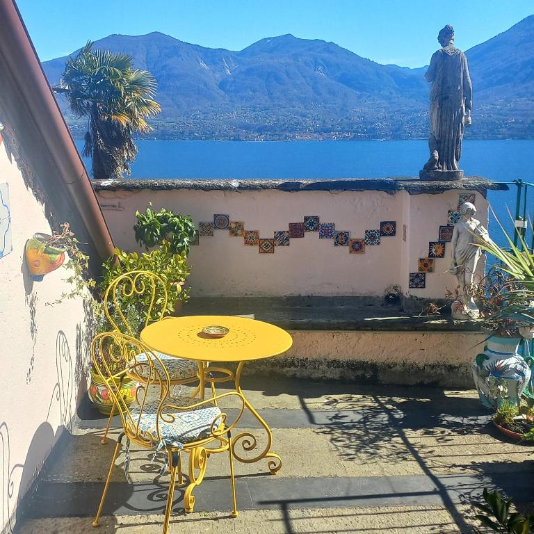 a table and chairs on a balcony with a statue at ANTICA CASA AL LAGO in Oggebbio