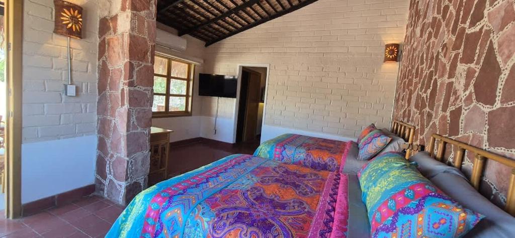 a bedroom with two beds and a stone wall at Sandy Shores Cabaña 7 in La Paz