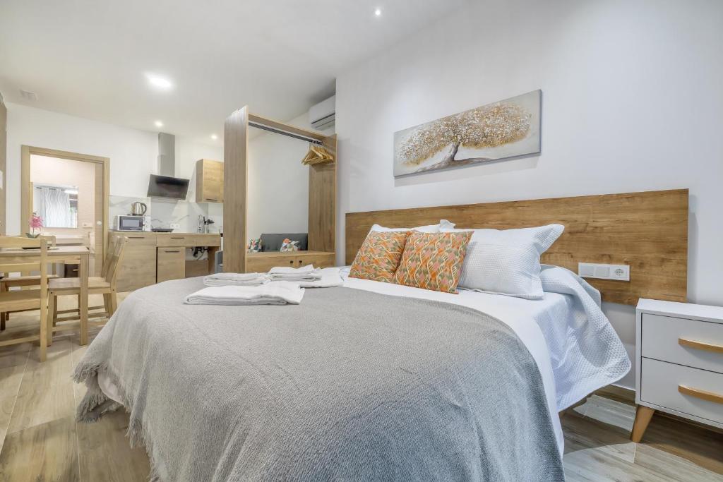 a bedroom with a large bed and a kitchen at Apartamentos Toril in Córdoba
