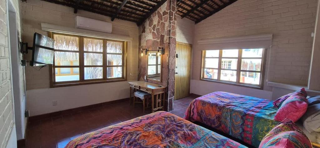 a bedroom with two beds and a table and windows at Sandy Shores Cabaña 8 in La Paz
