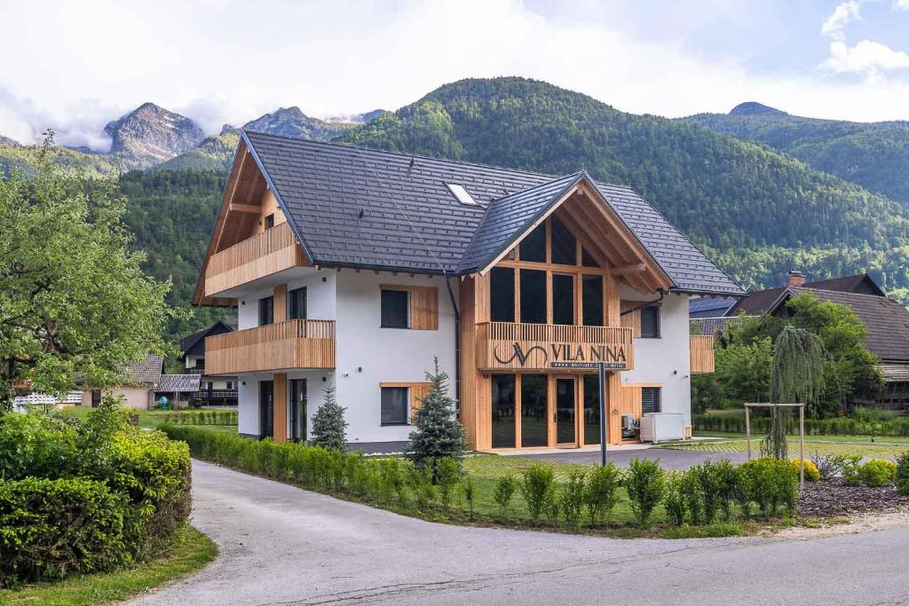 a large house with mountains in the background at Vila Nina Bohinj in Bohinj