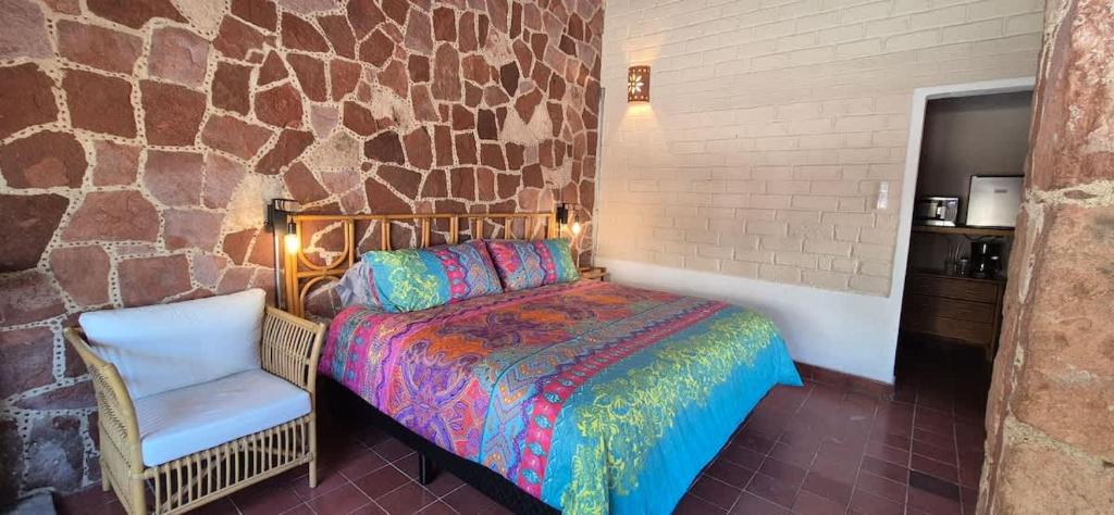 a bedroom with a bed and a chair and a stone wall at Sandy Shores Cabaña 10 in La Paz