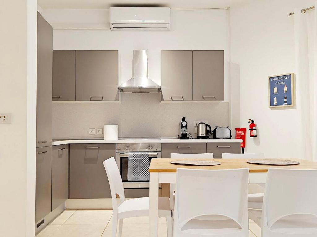 a kitchen with a wooden table and white chairs at Hilltop Retreat in Kalkara