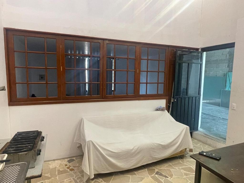 a room with a bed with a table and windows at Departamento MG in Puebla