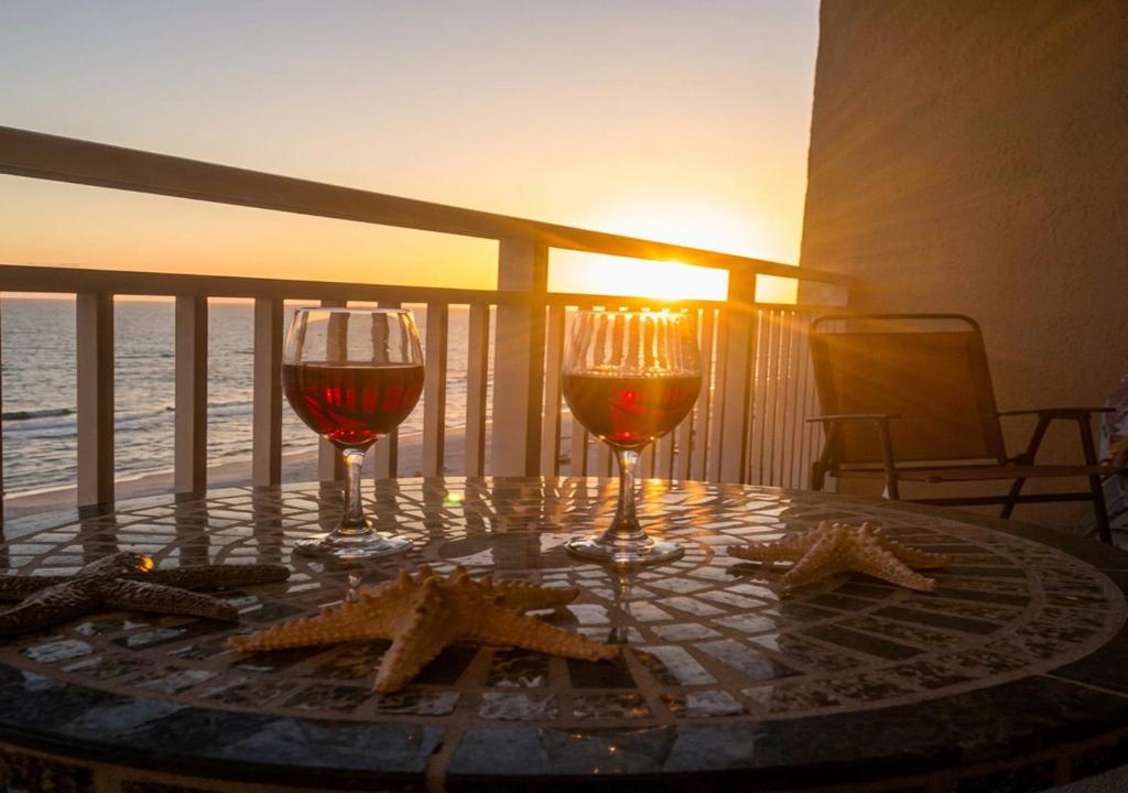 two glasses of wine sitting on a table on a balcony at Goin Coastal Emerald Beach Unit 729 in Panama City Beach