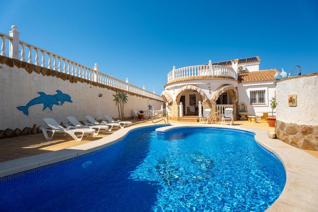 a villa with a swimming pool in front of a house at Enjoy complete seclusion at Casa Delfin, featuring your own stunning private pool and sunset views in Gran Alacant