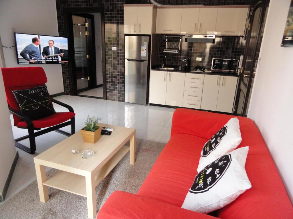 a living room with a red couch and a table at Diyarkom Apartment in Amman