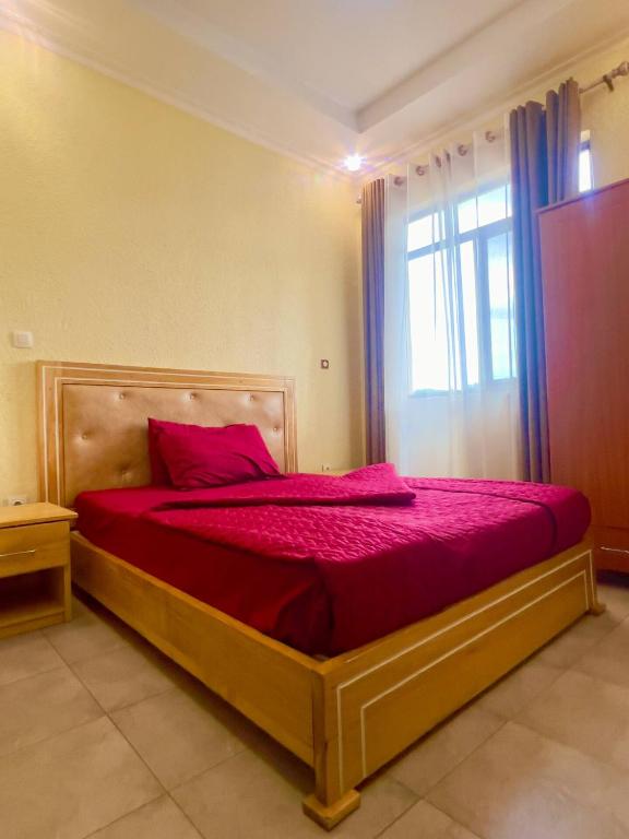 a bedroom with a bed with red sheets and a window at Centenary Gardens BnB in Kigali