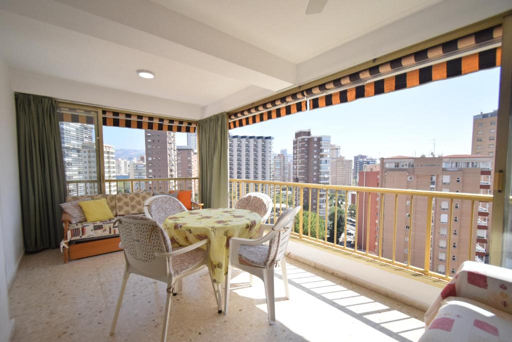 a balcony with a table and chairs and a large window at ADELFAS - Fincas Arena in Benidorm