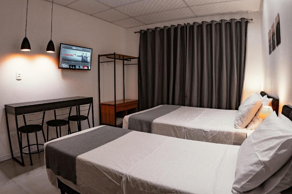a hotel room with two beds and a television at Urban Studio in Blumenau
