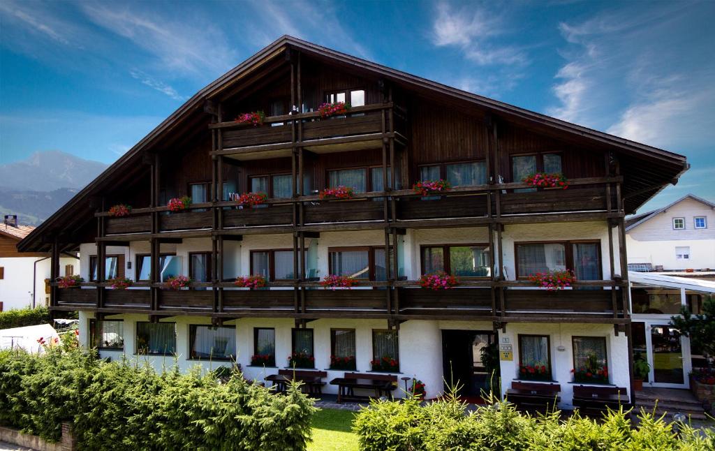 ein großes Holzgebäude mit Blumen auf den Balkonen in der Unterkunft Hotel Tirolerhof in Bruneck