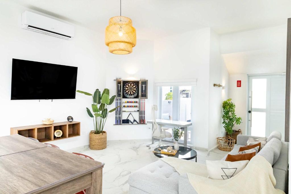 a living room with a couch and a tv on a wall at AQUA Casa A-8 - Vibrant & FUN 3 BR House with Pool in Dorado