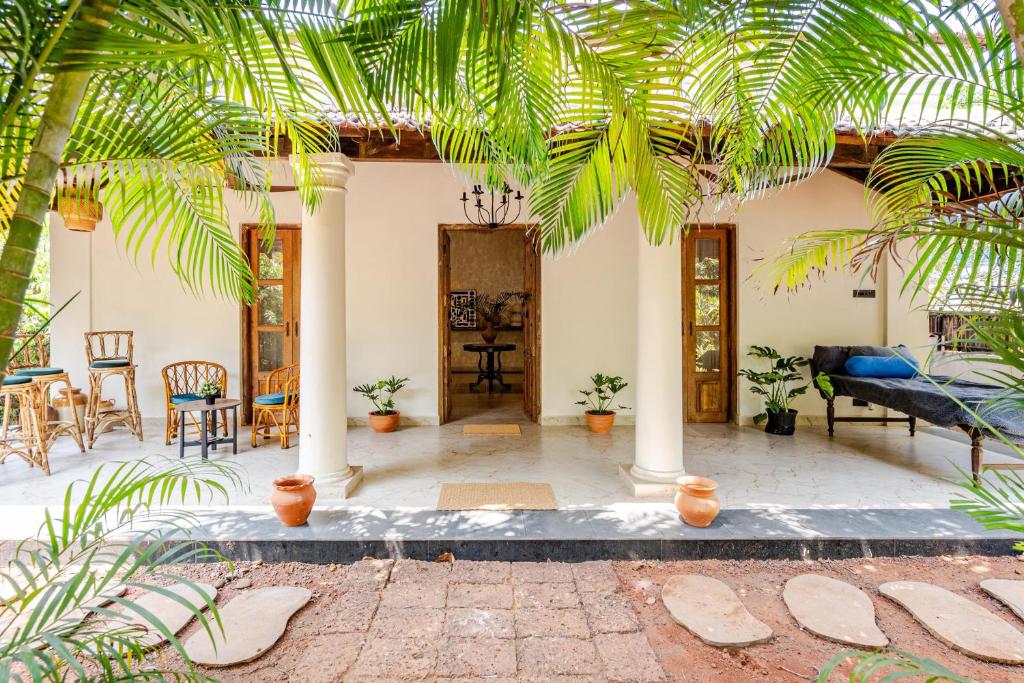 a house with a courtyard with palm trees at Casa Century Anjuna in Anjuna