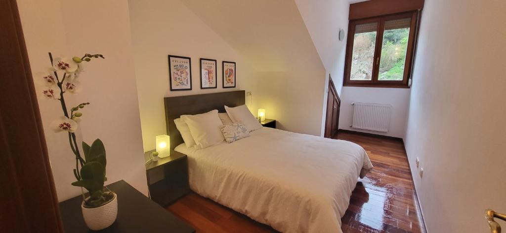 a bedroom with a bed with white sheets and a window at Ca Na Daniela in Carreña de Cabrales
